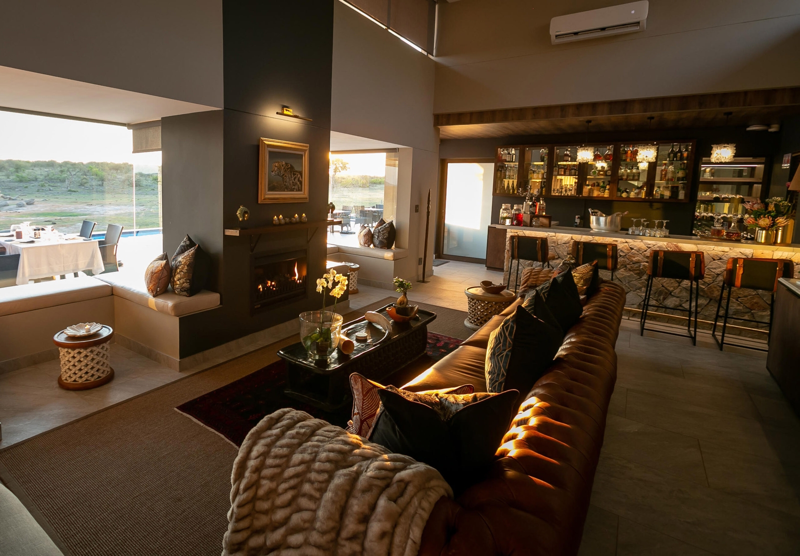 Elegant living room with fireplace, couch, and view of outdoor terrace at sunset.