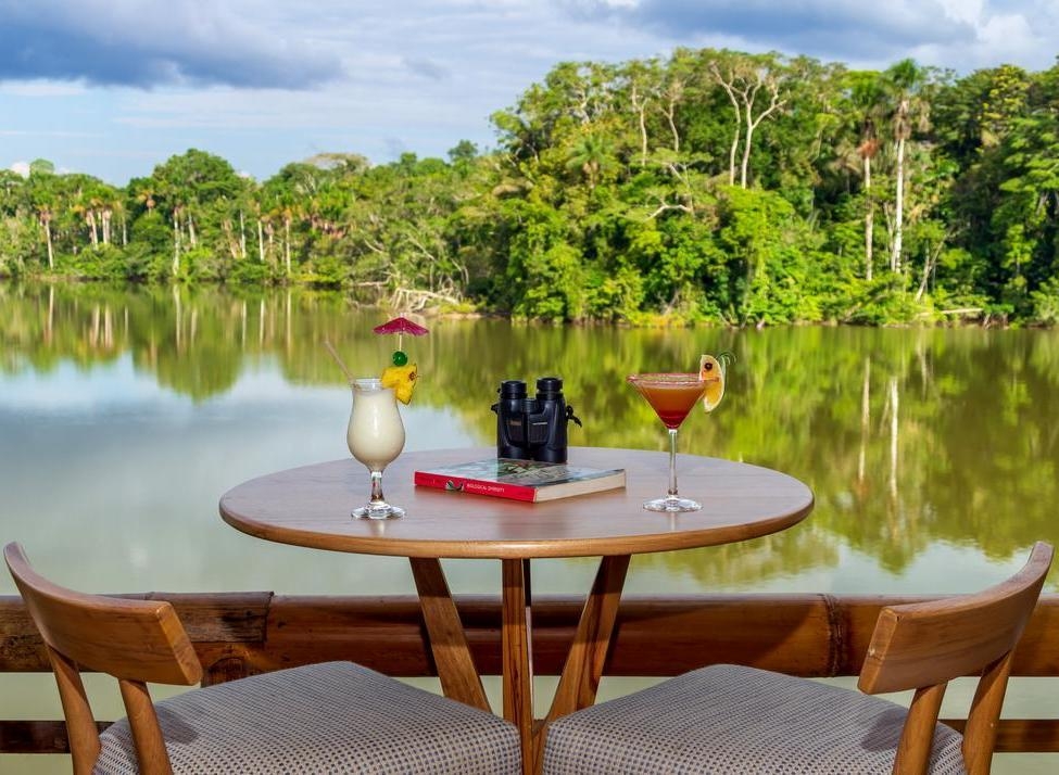 Two cocktails and a pair of binoculars on a table lagoon-side at La Selva Lodge.