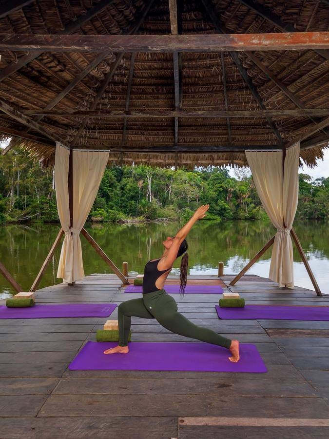 A person doing yoga on a lagoon-side pavillion.