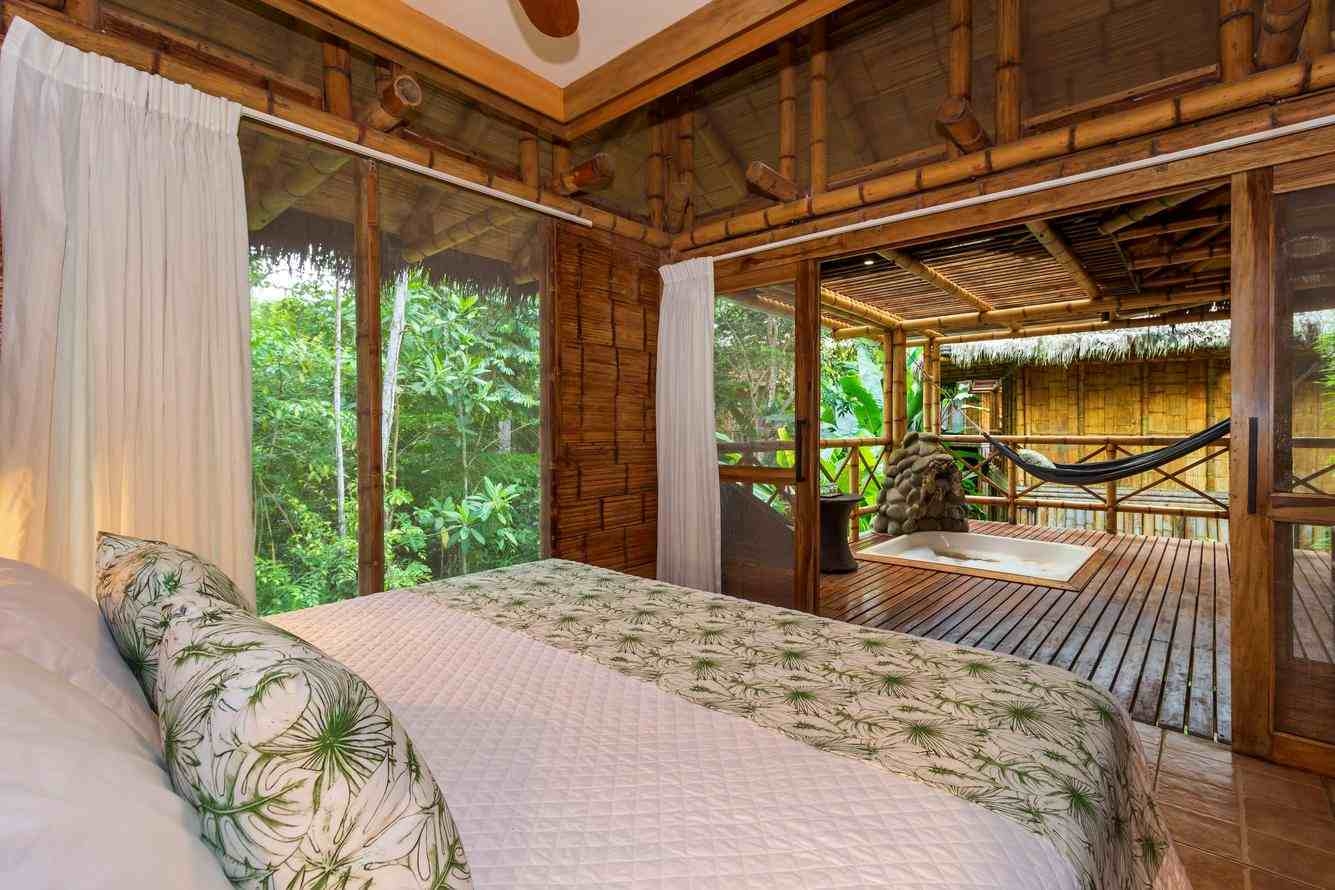 A bedroom at La Selva Lodge which leads onto a wooden terrace with a sunken hot tub.