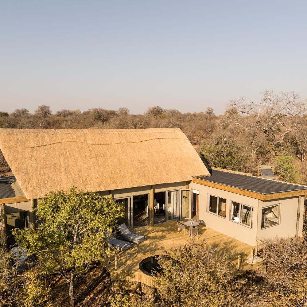 An aerial view of a large thatched-roof luxury tent and deck at Victoria Falls River Lodge.