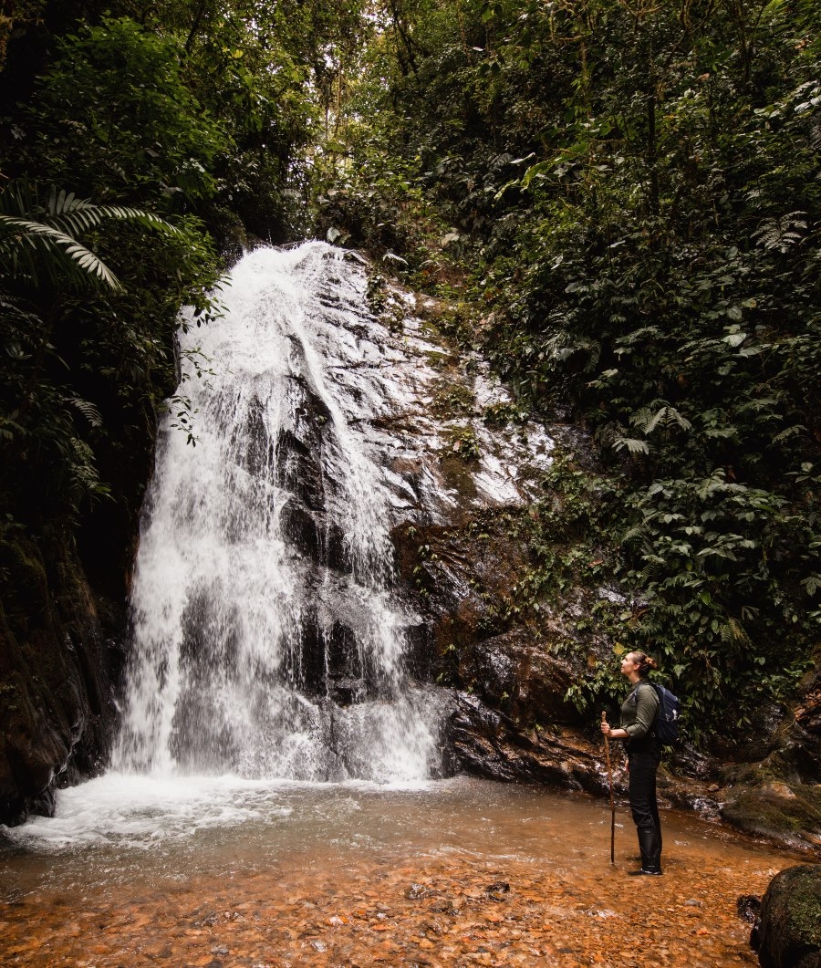 A person standing at the base of a waterfall.