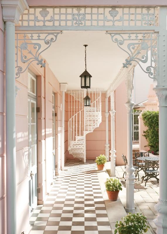 A pink veranda at Mount Nelson Cape Town with checkered floors and a white metal spiral staircase.