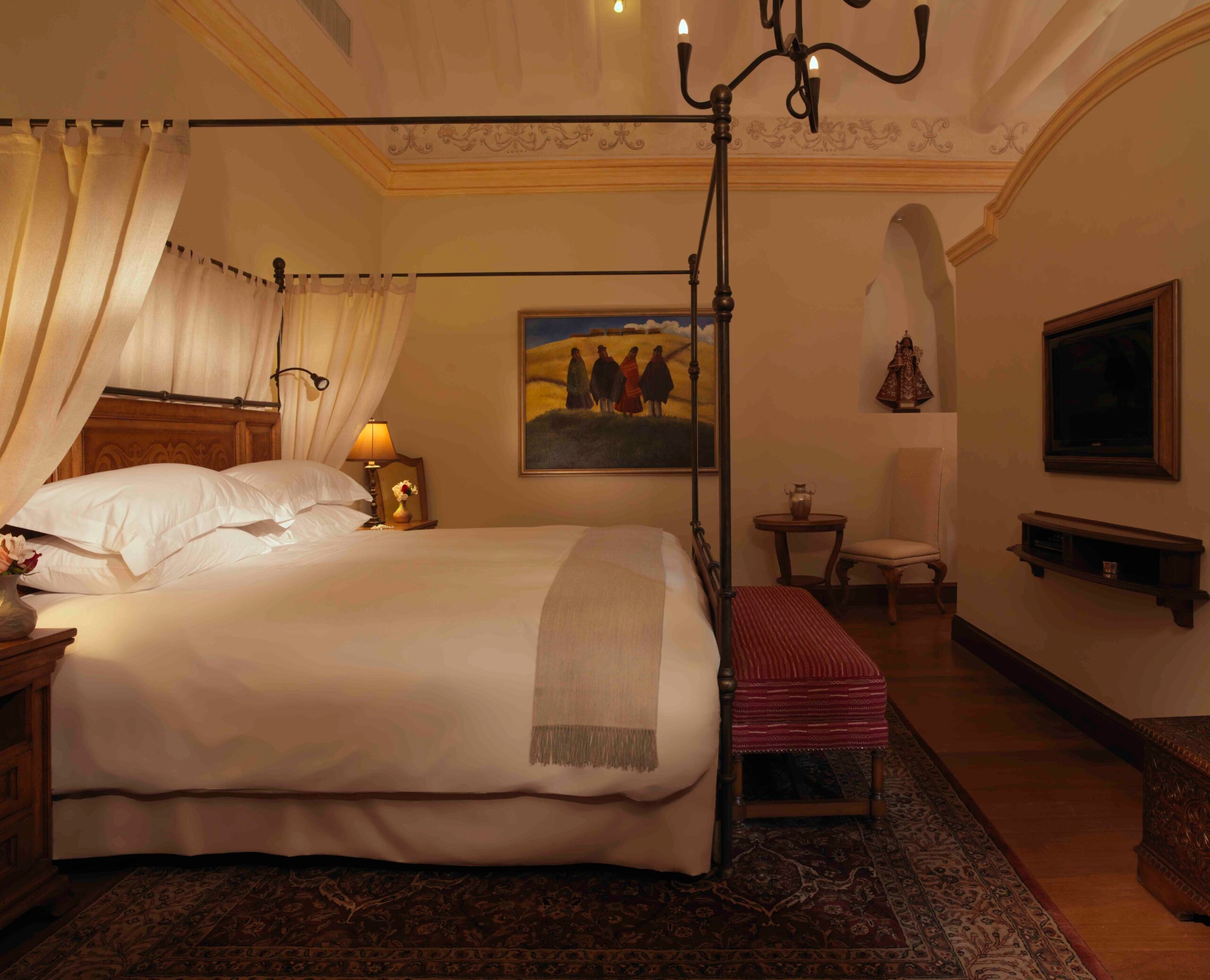 Elegant bedroom with a four-poster bed, soft lighting, paintings, and classic decor.