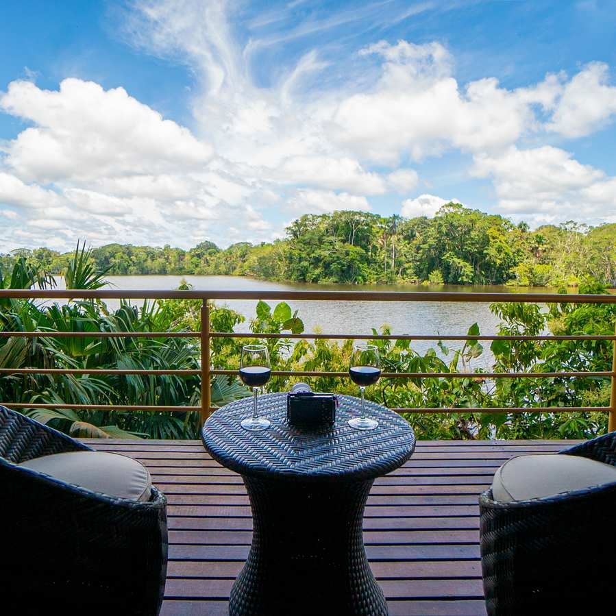 A panoramic terrace at La Selva Lodge where two chairs and a table overlook the lagoon ahead.