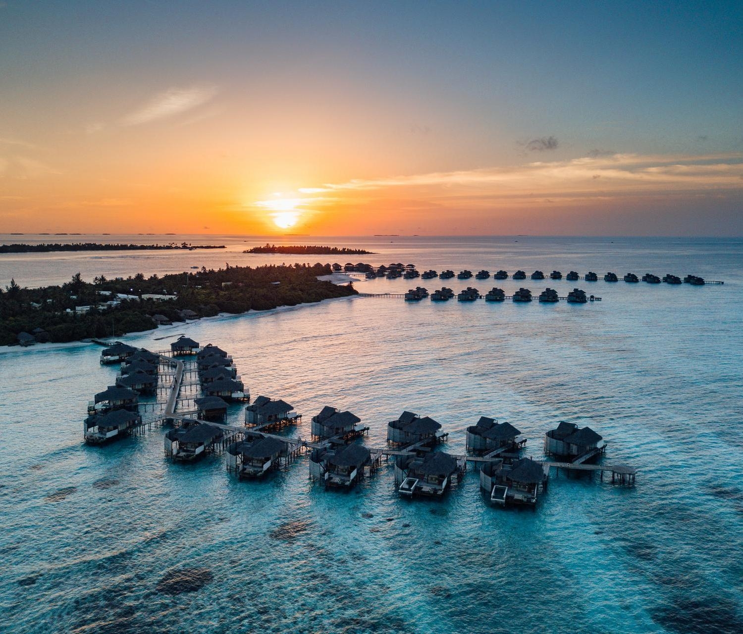 Aerial view of overwater villas at sunset at Six Senses Laamu