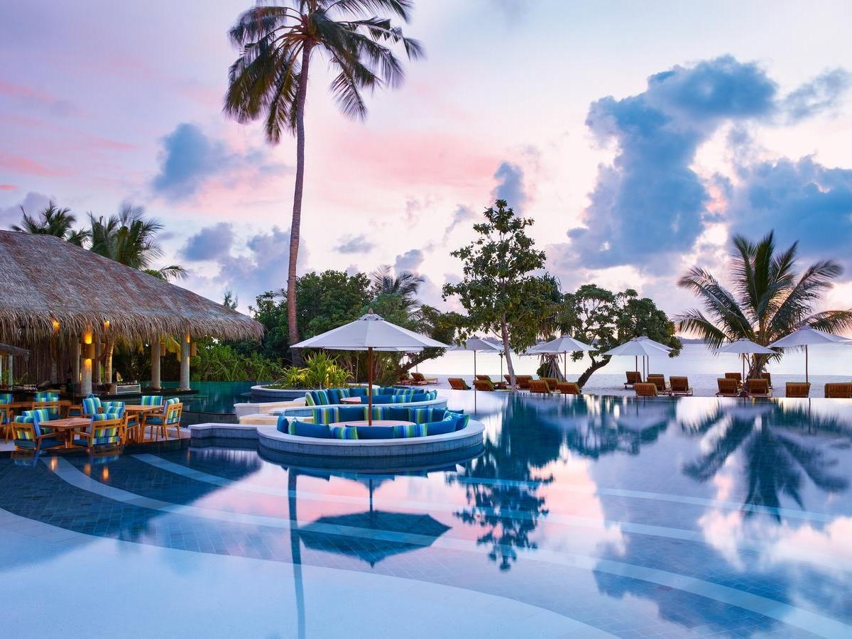 Infinity pool with sunken seating area at sunset at Six Senses Laamu