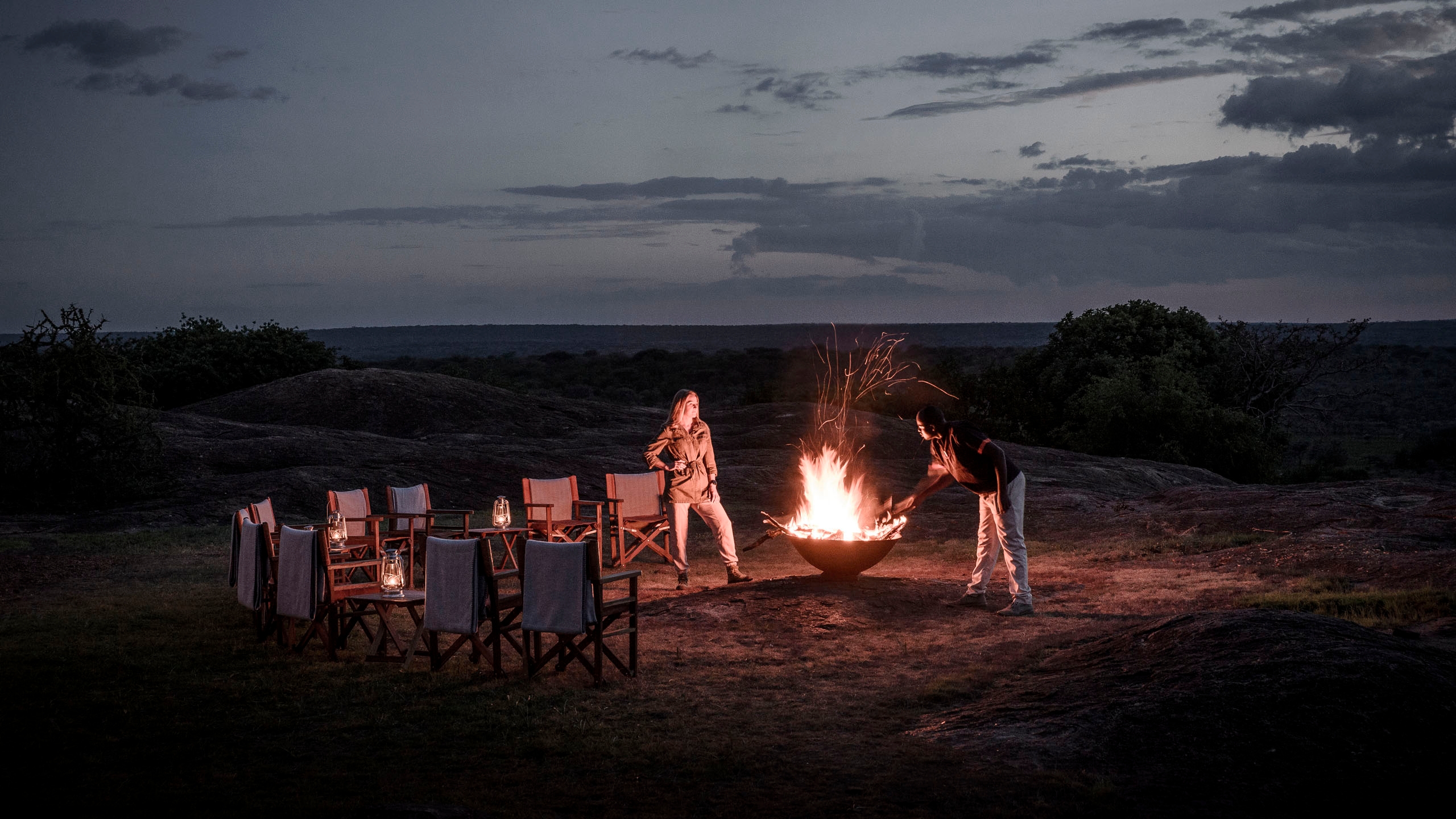Two people around a fire at night in the Serengeti