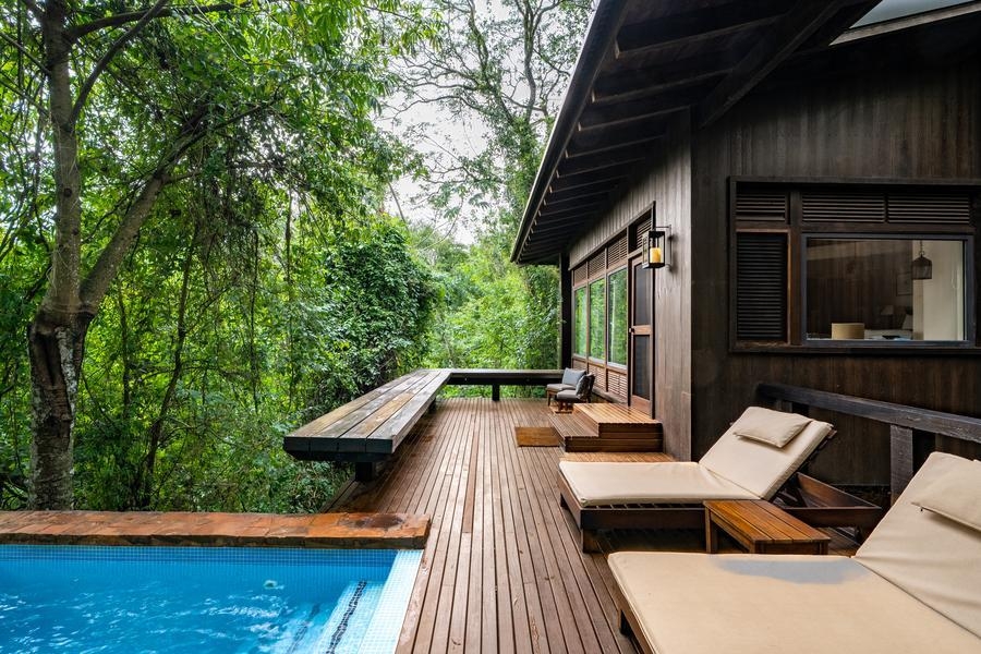 A wooden villa surrounded trees at Awasi Iguazu featuring a pool.