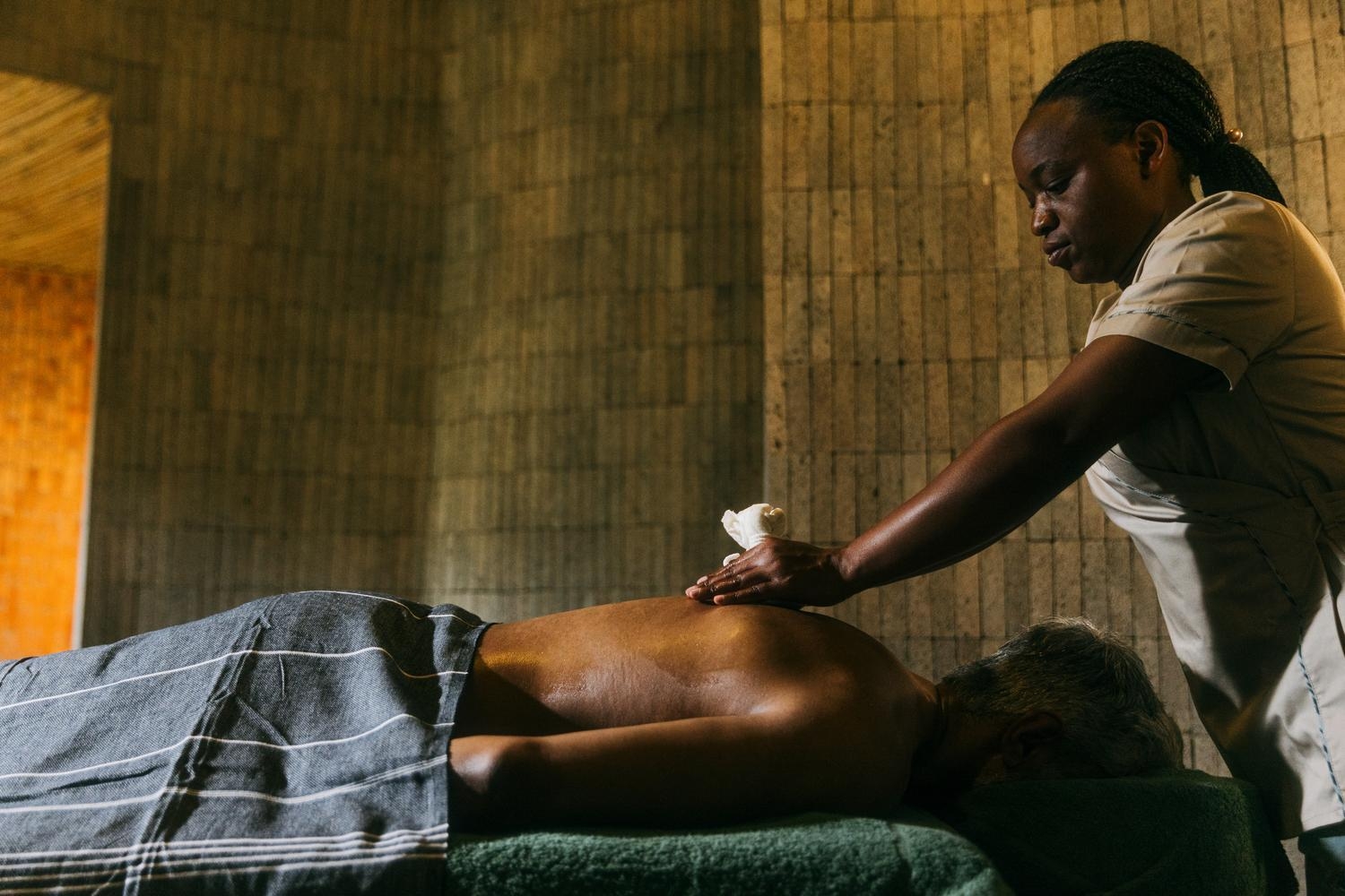 A woman giving a back massage to a person at The Sanctuary at Wilderness Bisate