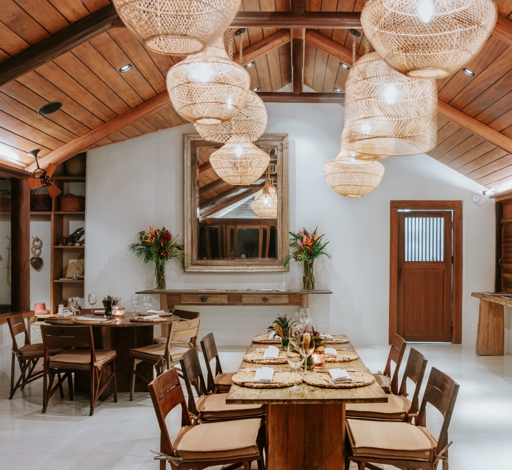Elegant dining room with woven pendant lights, wooden table set for dinner, and exposed beams.