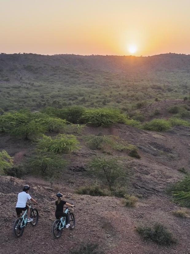 Two people mountain biking in the surrounding area at Six Senses Fort Barwara.