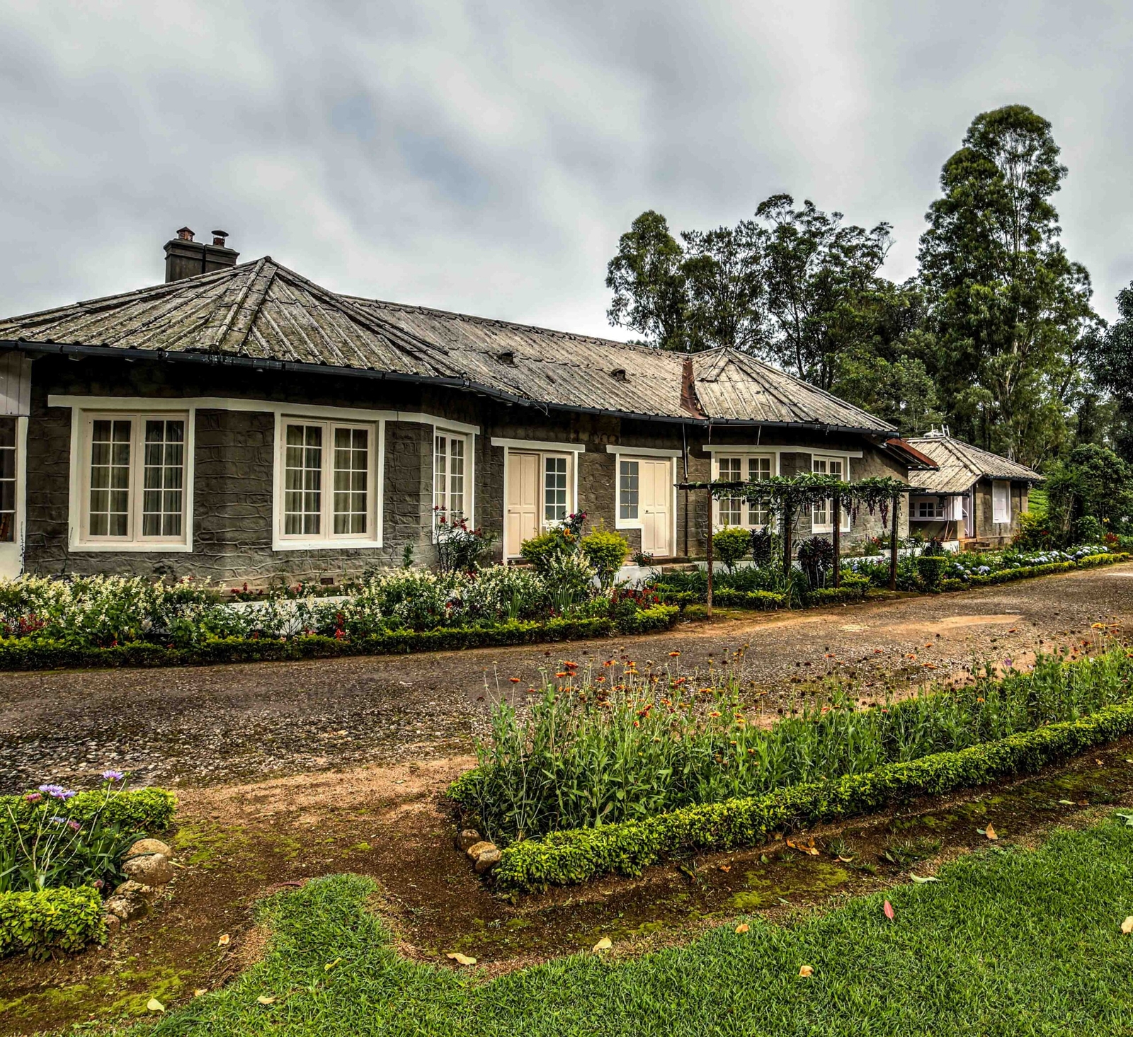 Charming old cottages with flower gardens under a cloudy sky.