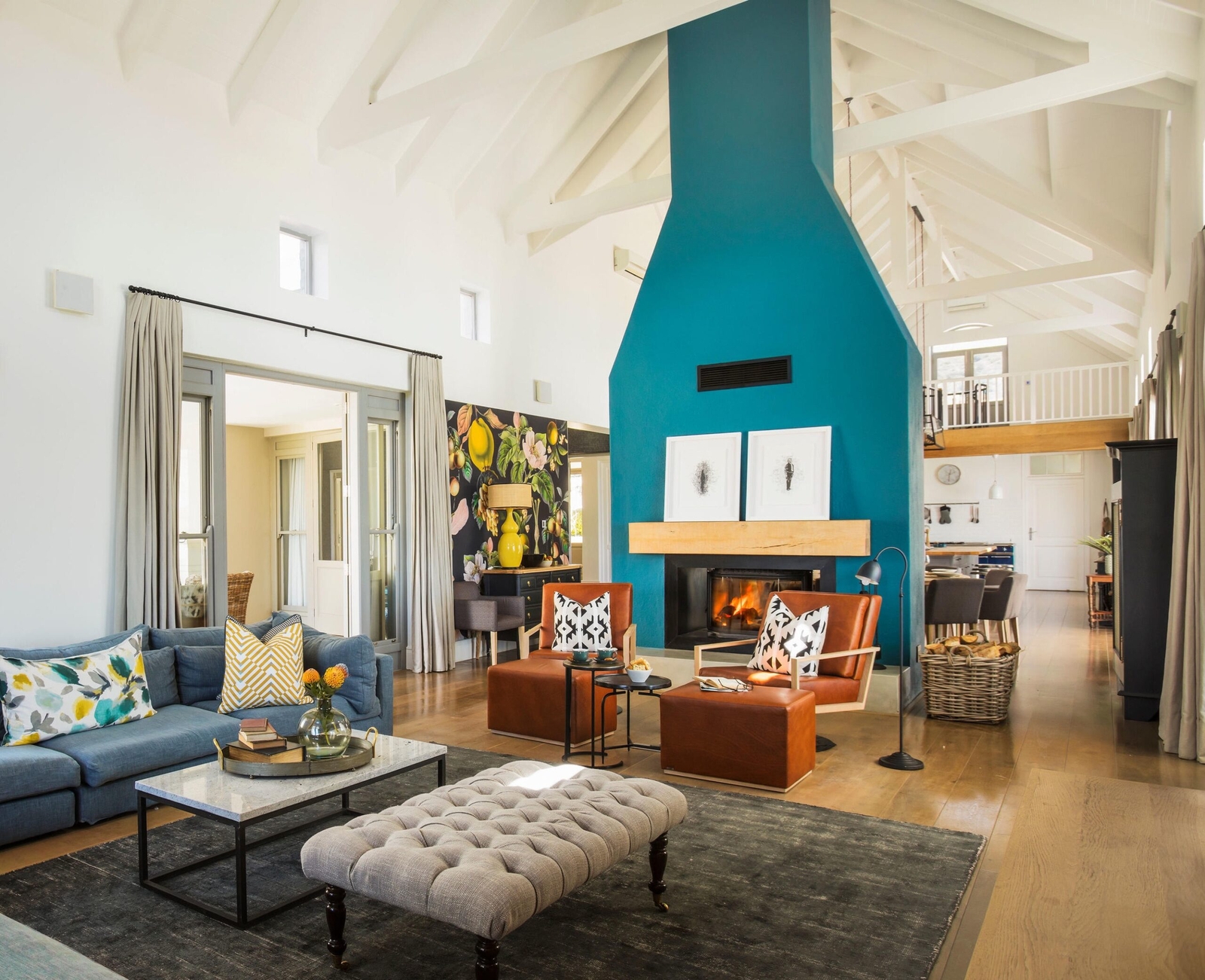 Bright living room with blue fireplace, high ceiling, beige sofa, and eclectic decor.