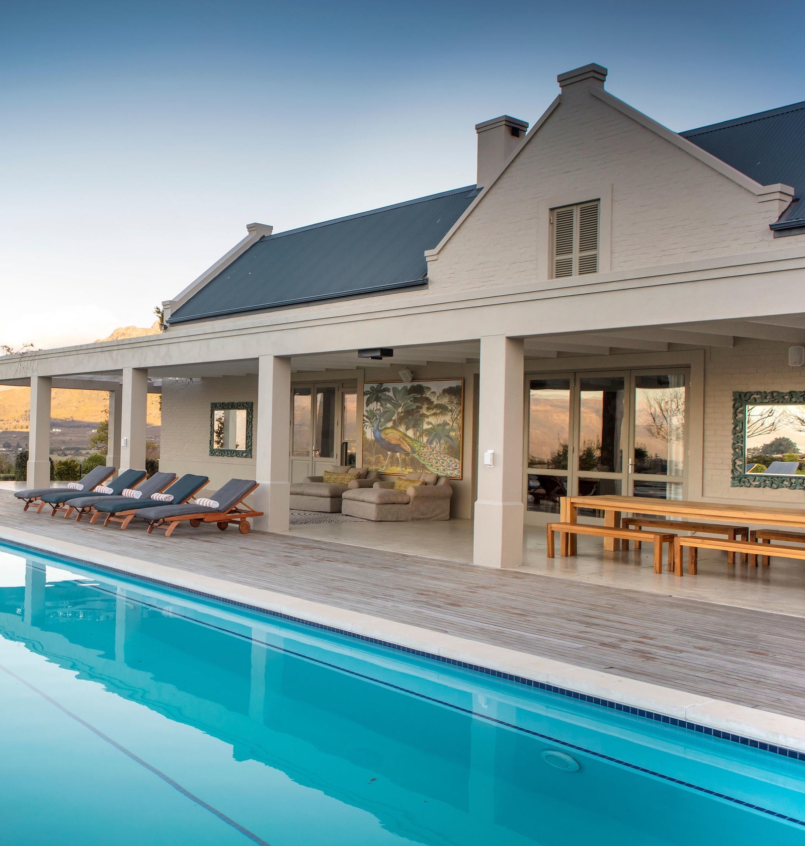 Luxury house with a pool, patio, and mountain view at dusk.
