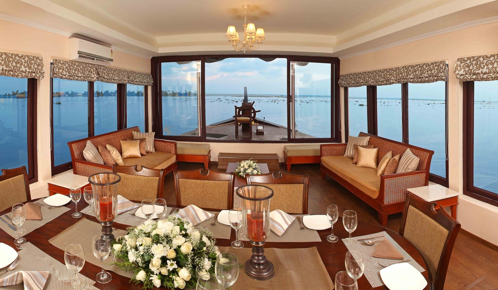Elegant dining area with a panoramic view of a tranquil lake, set for a luxurious meal.