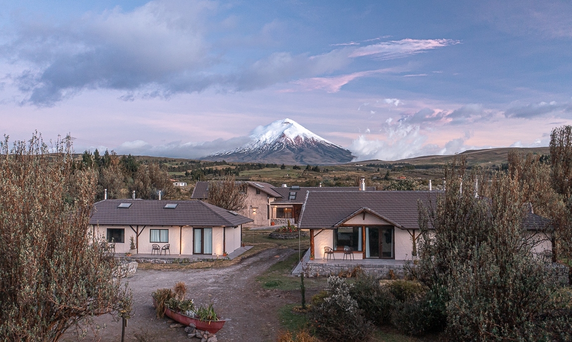 Rural houses with a snow-capped volcano in the background at dusk.