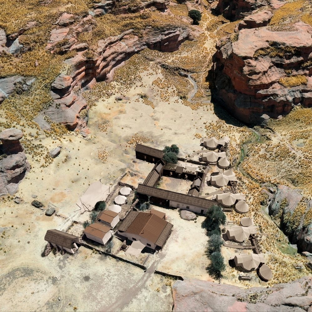 Aerial view of a desert resort with tents and buildings nestled among rocky terrain.