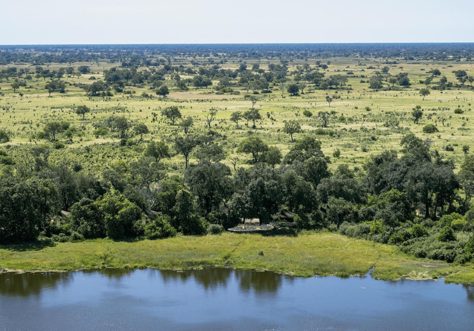 An aerial view of Maxa Camp, which sits on the edge of a lagoon between mature trees.