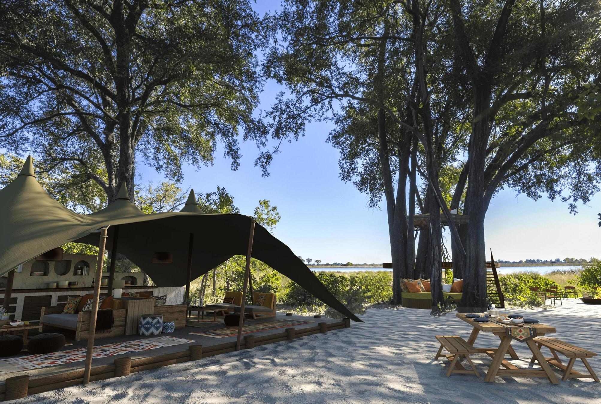The communal area of Maxa Camp, featuring a cushioned lounging area beneath a canvas roof. There's also a courtyard with picnic style tables.