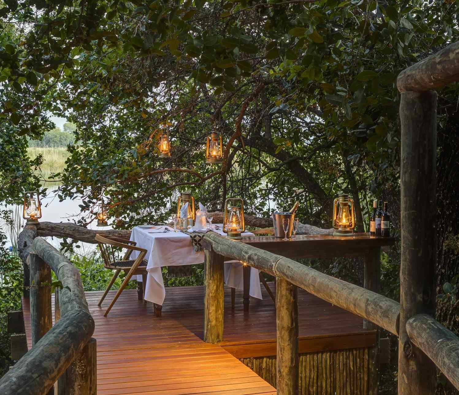 Private dining at Shinde Camp in an area lit by lanterns between a cluster of trees.