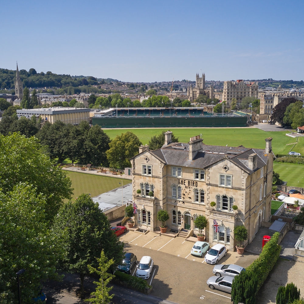 Aerial view of The Bird hotel showing surrounding green areas and Bath city centre in the background