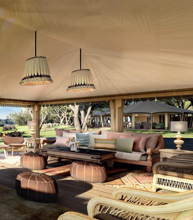 A cosy lounge with layered rugs, hanging lamps and seating areas facing an open field with a distant elephant.