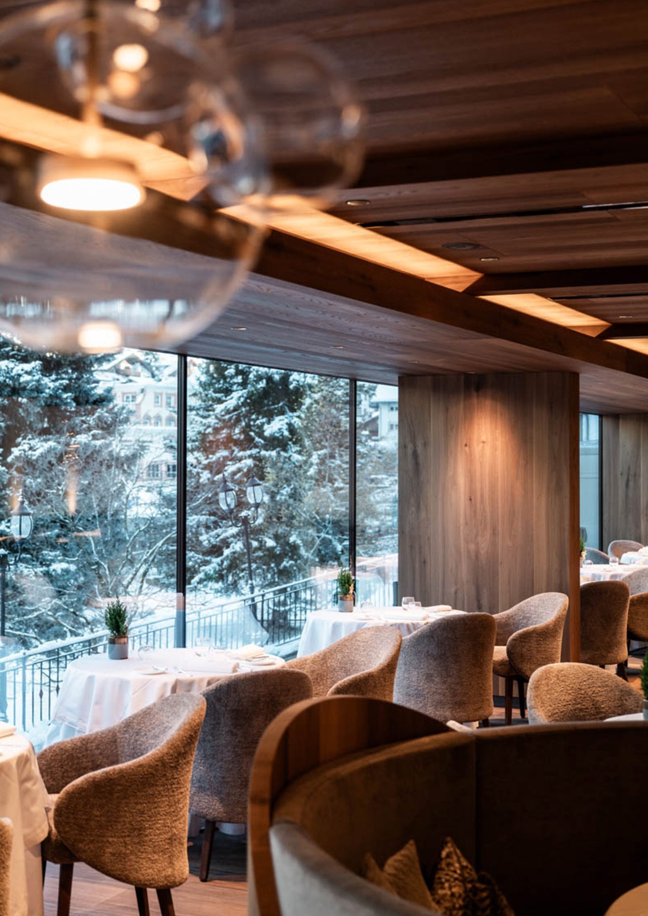 Interior of a bar area with grey plush seats overlooking windows with a snowy winter scene outside.