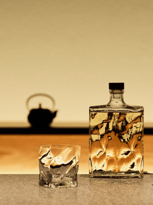 Textured whisky bottle with a glass next to it