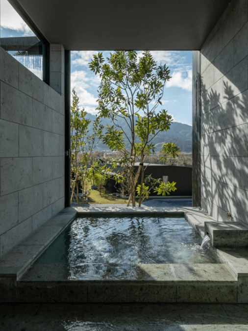 Outdoor sunken stone bath with a tree in the background