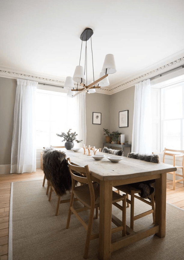 A bright dining area with a light wood table and chairs on a beige rug