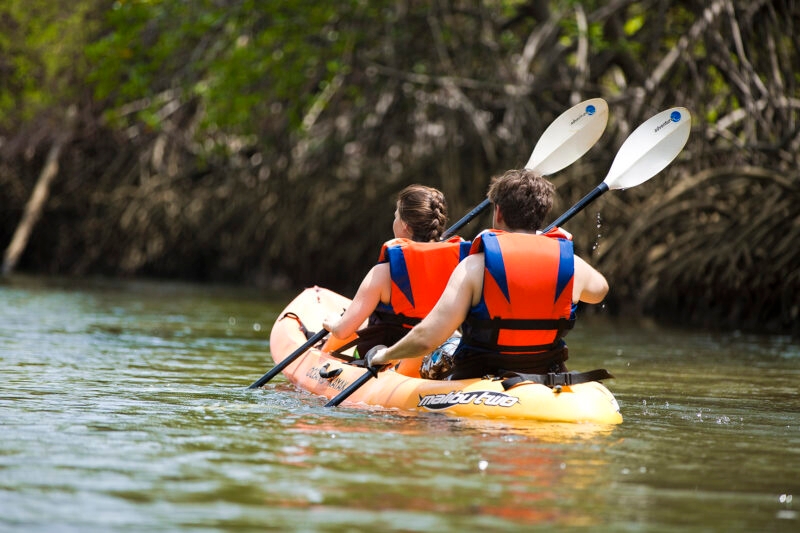 Luxury Costa Rica tours - two people in life vests paddling a kayak on a still river in a rainforest