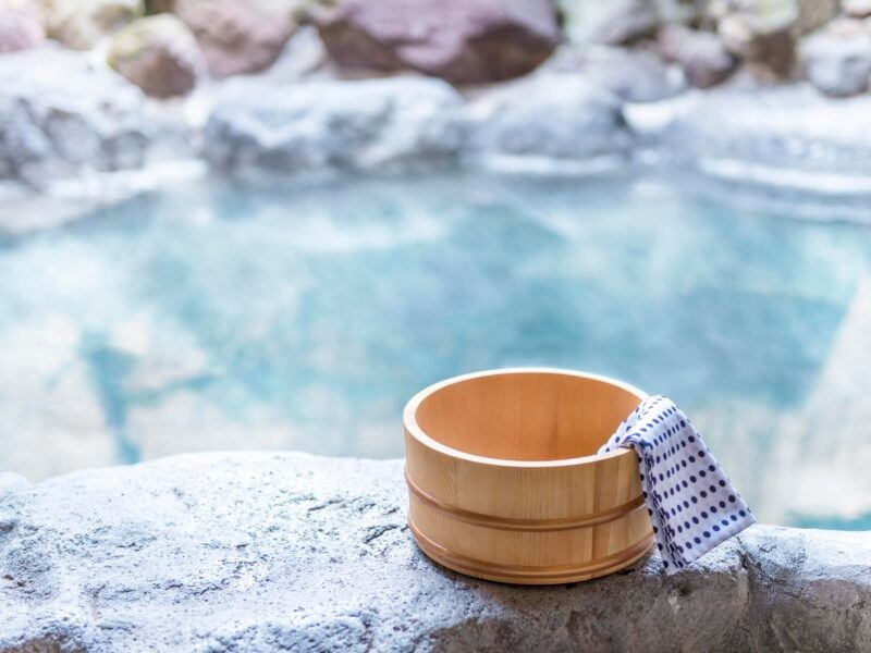 Private Japan Luxury Tours- Japanese hot spring, open-air bath with wooden pot and blue and white spotted towel on the edge