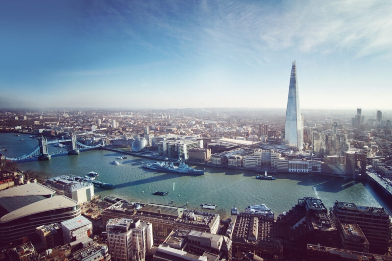 Aerial view of London featuring the River Thames, the Shard skyscraper, and the historic Tower Bridge.
