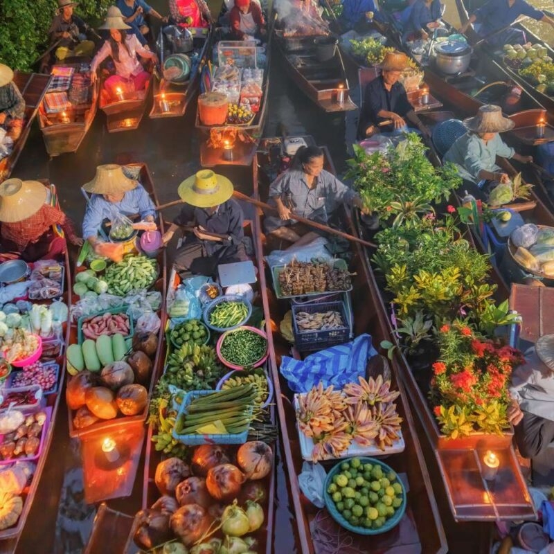 Busy floating market with boats full of produce on luxury Southeast Asia vacations.