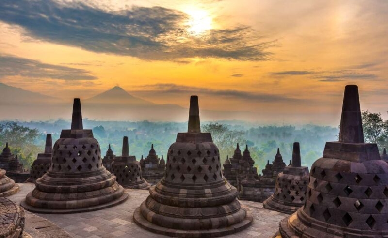 Stone stupas at sunrise with a mountain view during luxury Southeast Asia trips.