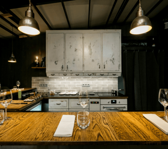 Elegant kitchen with distressed cabinets, set for dining, and pendant lighting.