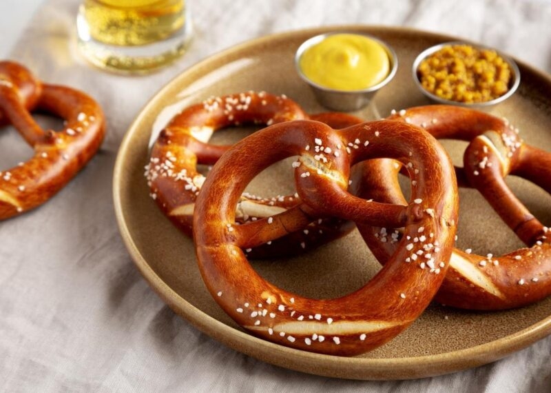 Plate with salted pretzels and mustard dips on a table.