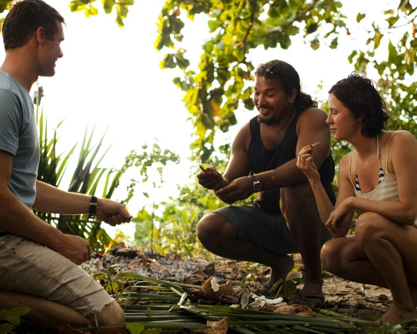 People crouch in the bush to talk about plant species