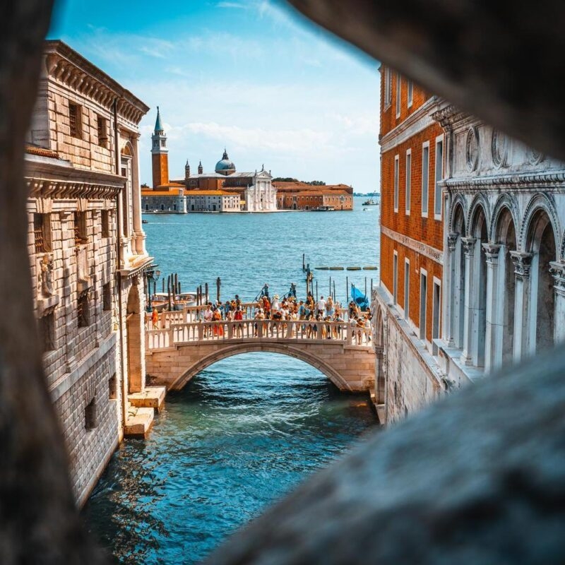 A bridge over the Grand Canal in Venice seen through a gap in some stonework