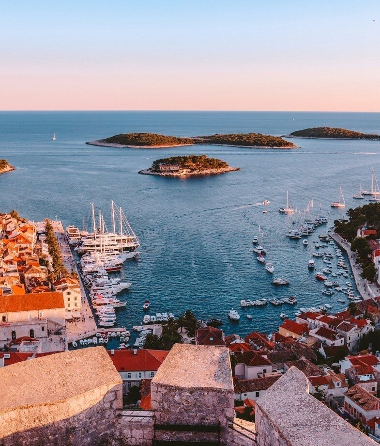 Turquoise waters along a quiet cove in Mallorca, Spain, and sunset views over Hvar’s harbour and islands in Croatia.