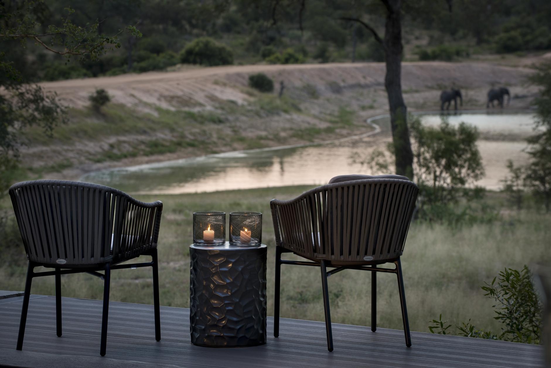 A pair of chairs on the terrace of one of Chitwa Chitwa's accommodations overlooking a waterhole.