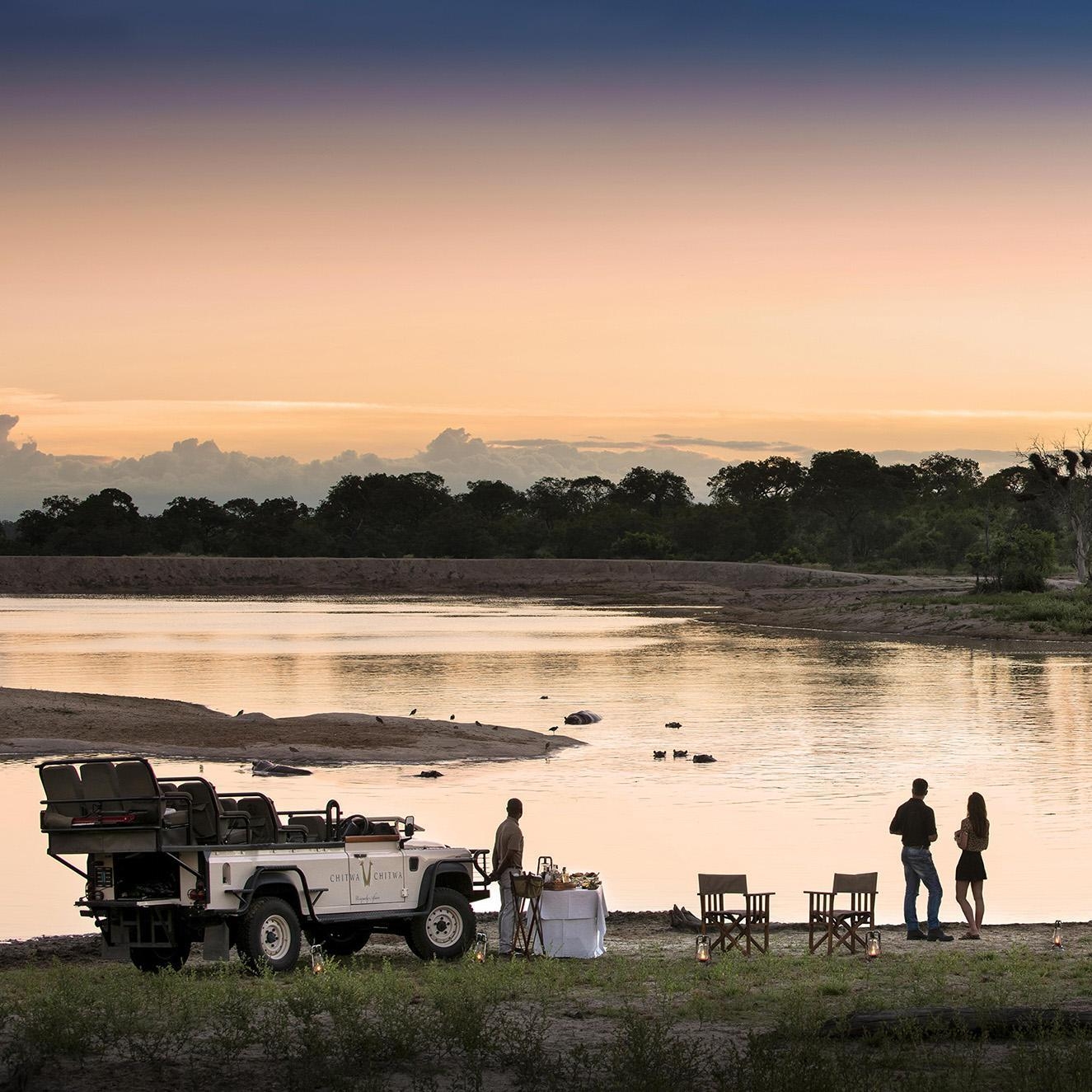 A couple participating in sundower drinks by a body of water.