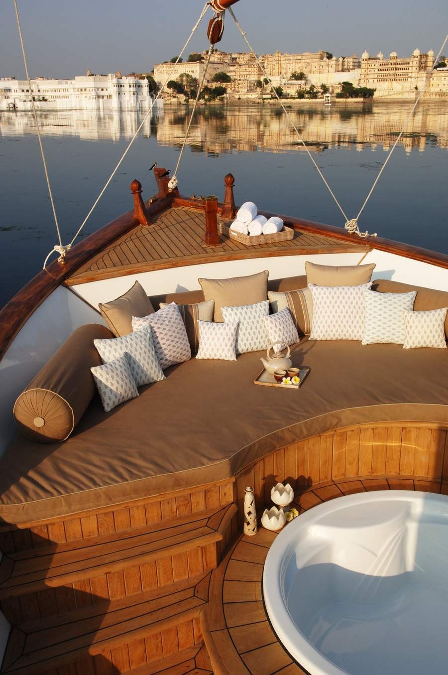 The Taj Lake Palace's wooden spa boat featuring a cushioned seating area and a sunken hot tub.