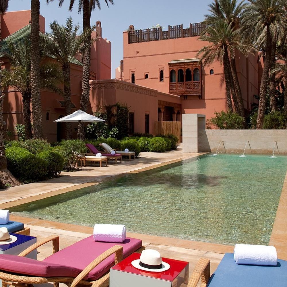 A long outdoor swimming pool with pink and blue loungers at the luxury Royal Mansour resort in Marrakech.