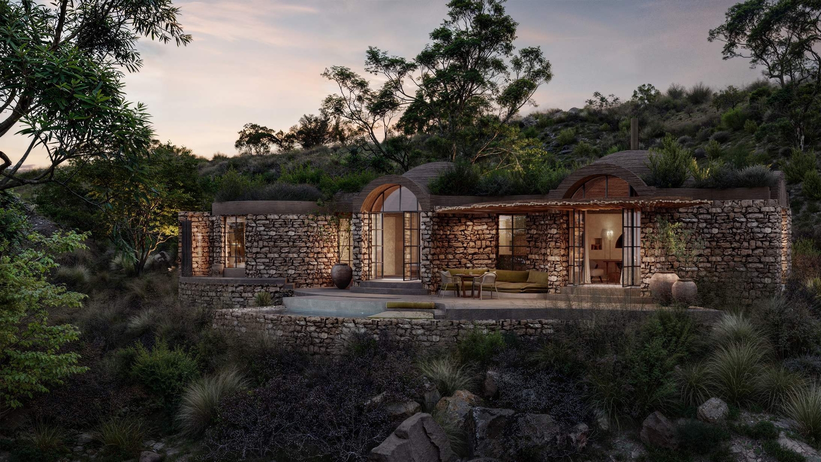 Stone house with arched doors nestled in a lush, tranquil hillside at dusk.