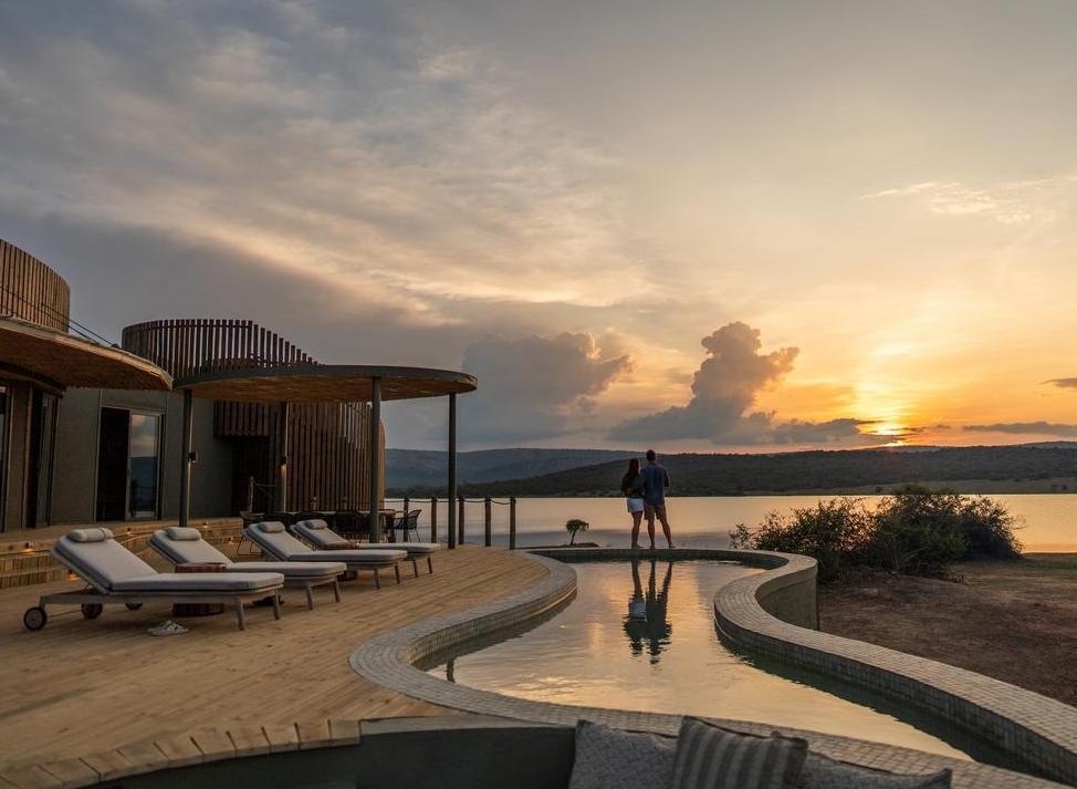 A couple stand by a pool at Wilderness Magashi Peninsula a luxury lodge in Rwanda.