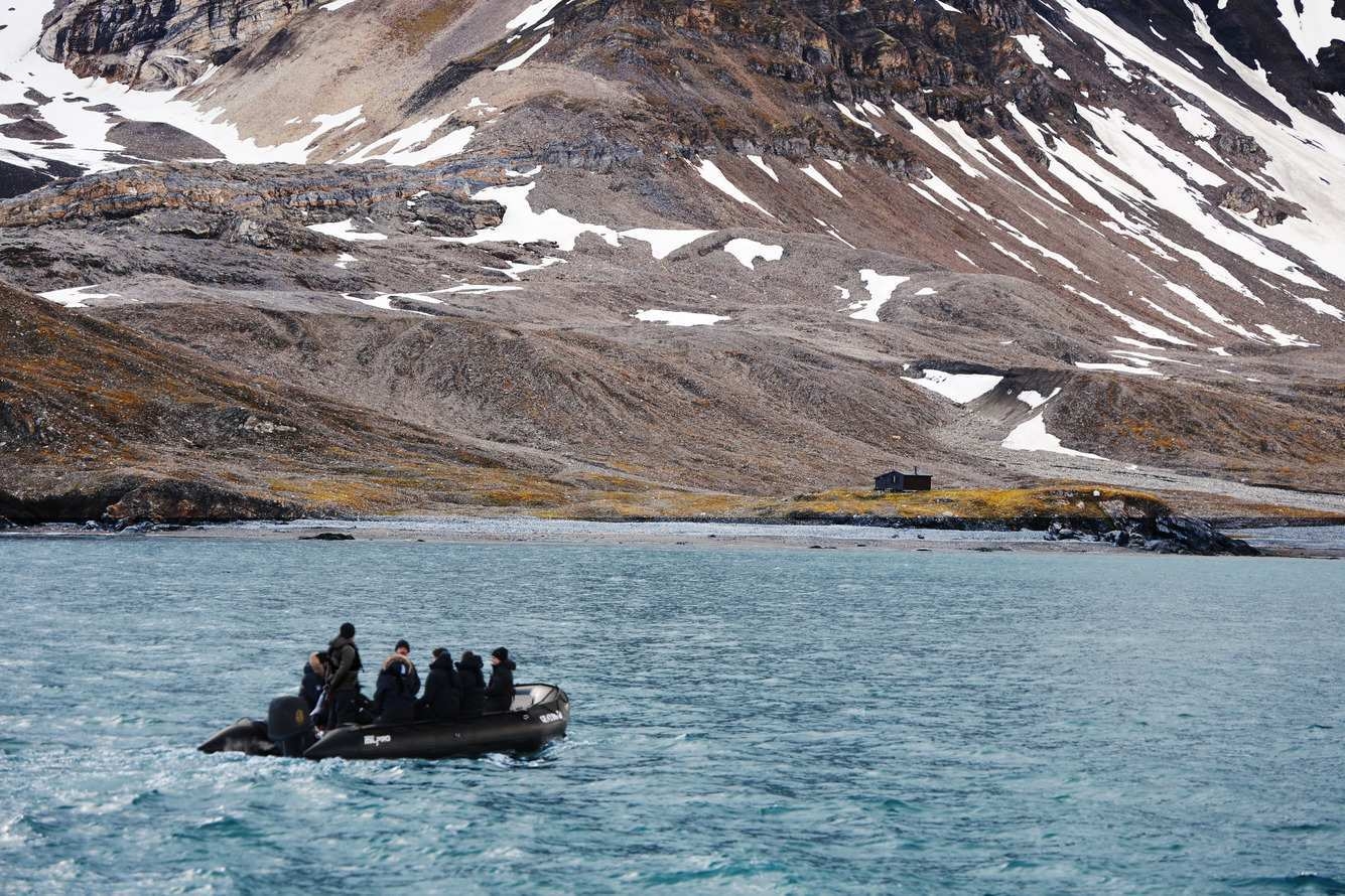 A group of people on a Zodiac excursion in the Arctic with a mountain in the background.