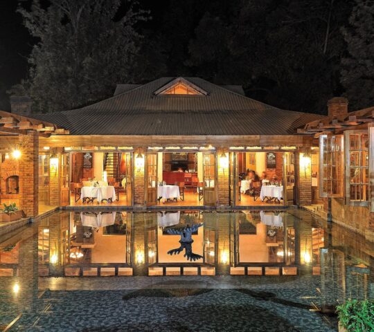 View of the dining room of Arusha Coffee Lodge from across the fountain at night, Arusha Tanzania