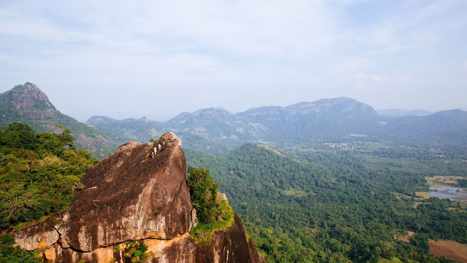 The ancient rock fortress of Sigiriya as seen from afar with foliage-cloaked mountains in the backdrop in Sri Lanka.